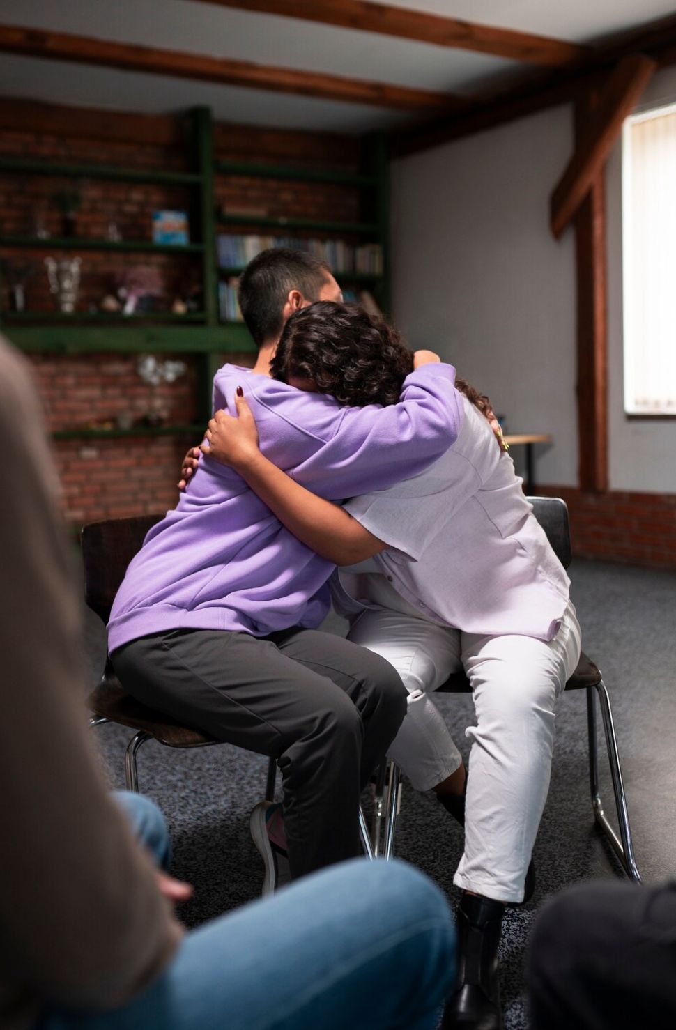 Two people embrace during a support group session