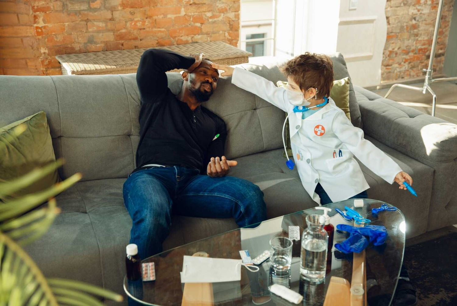 A child in a toy doctor's coat checks on his father at home